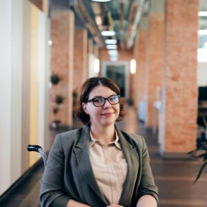 Professional businesswoman in a wheelchair smiling confidently in modern office.